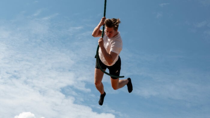 Nuori henkilö heiluu ilmassa köyden varassa.